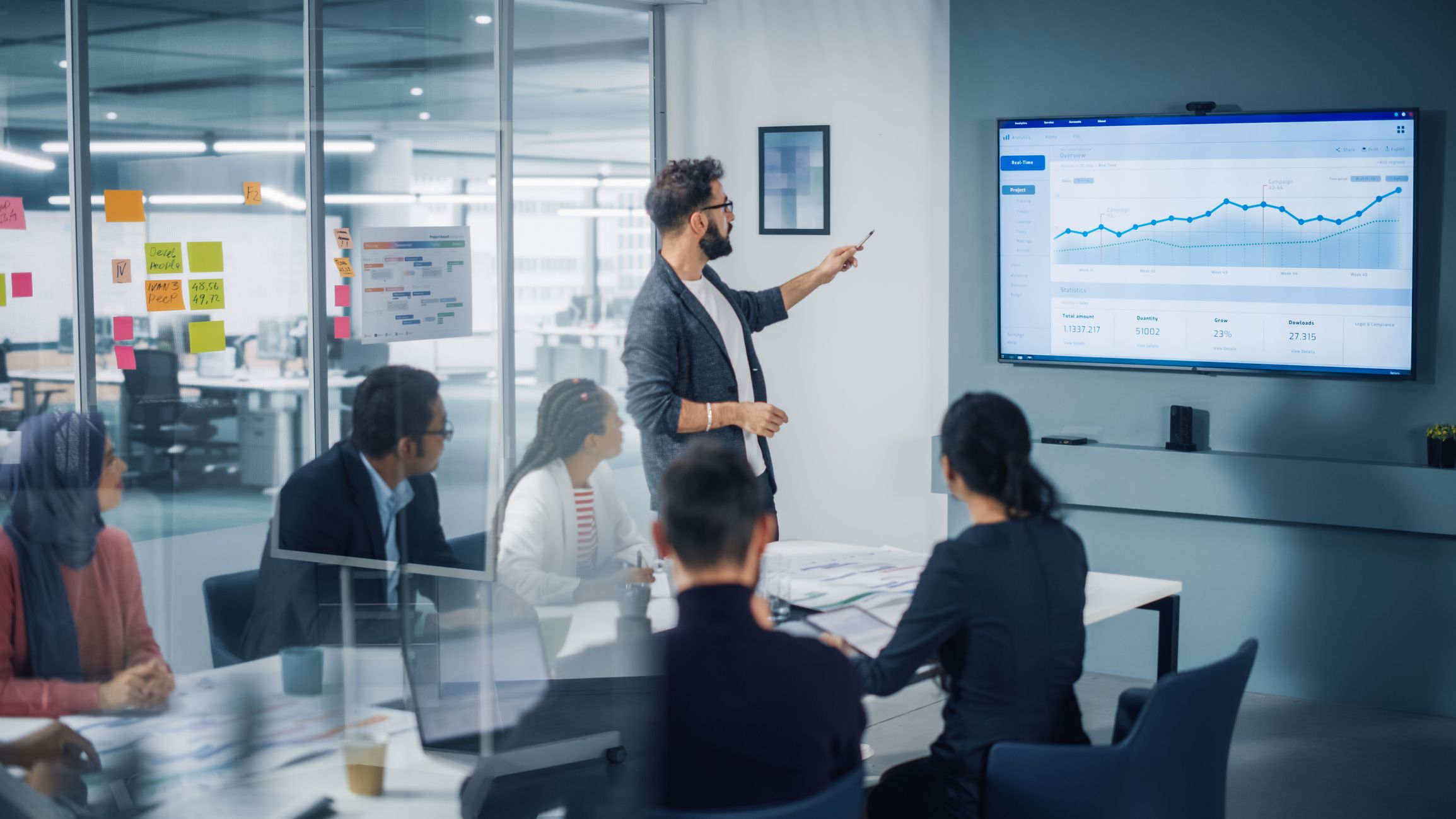 Diverse Modern Office: Motivated Businessman Leads Business Meeting With Managers, Talks, Uses Presentation Tv With Statistics, Chart Growth, Big Data. Digital Entrepreneurs Work On E Commerce Project